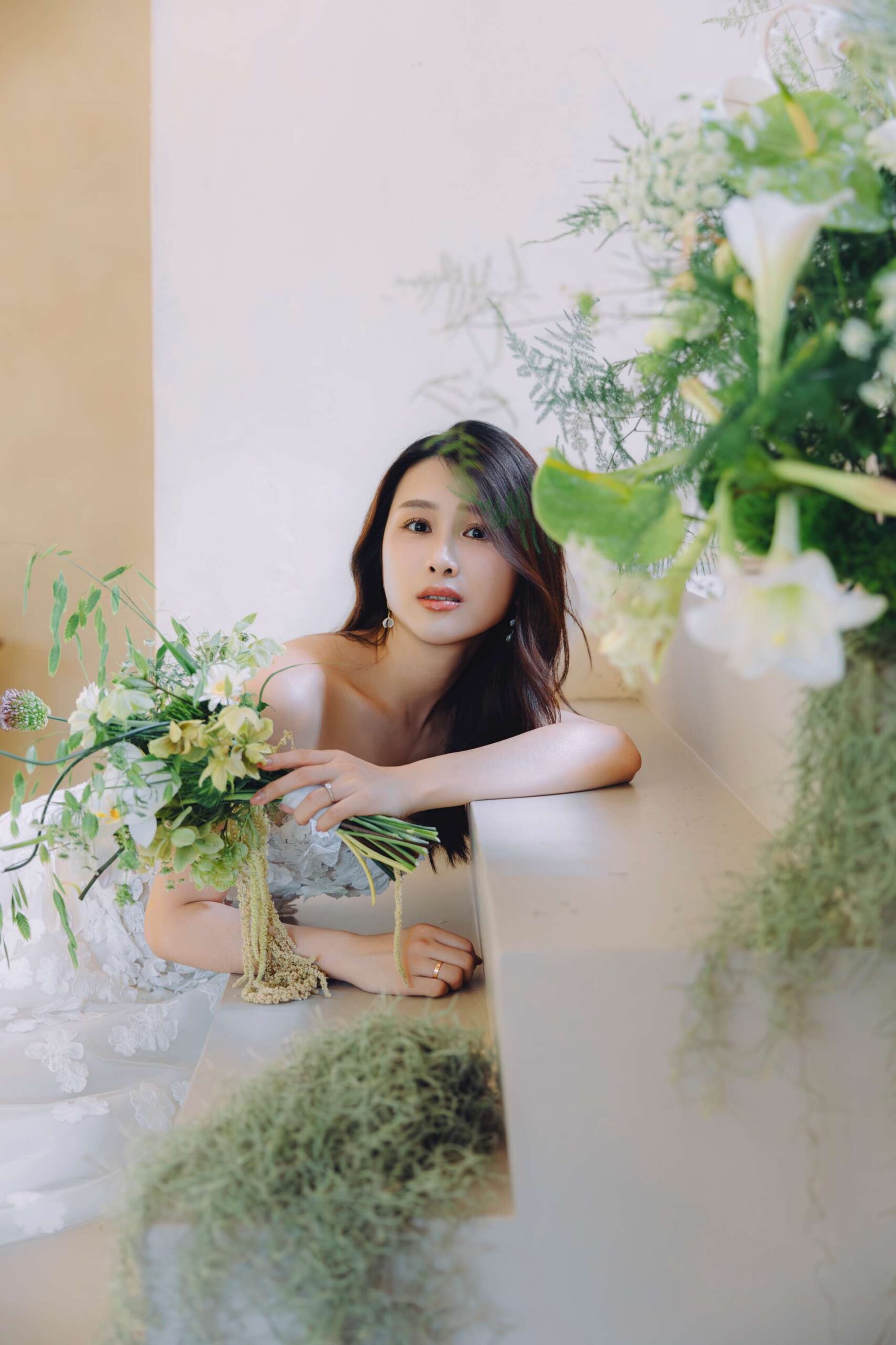台北新娘妝髮推薦,荳荳小姐打造清透高級感新娘妝容特寫,新娘手捧清新花藝靠在石階上。