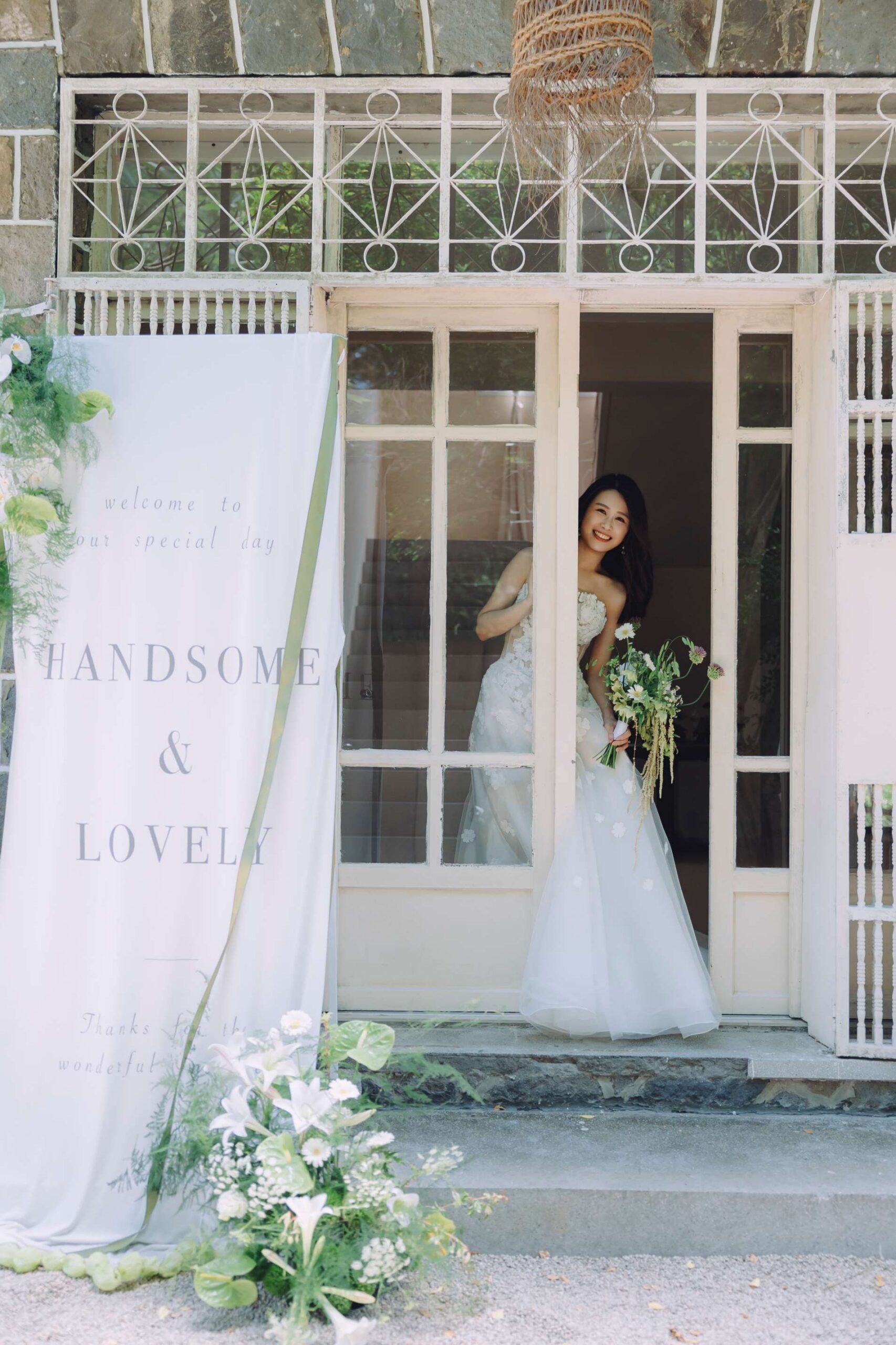台北高質感婚紗工作室靜好美學,新娘身穿蒂米琪精品婚紗與新郎於歐風老建築石牆門廊前合照。