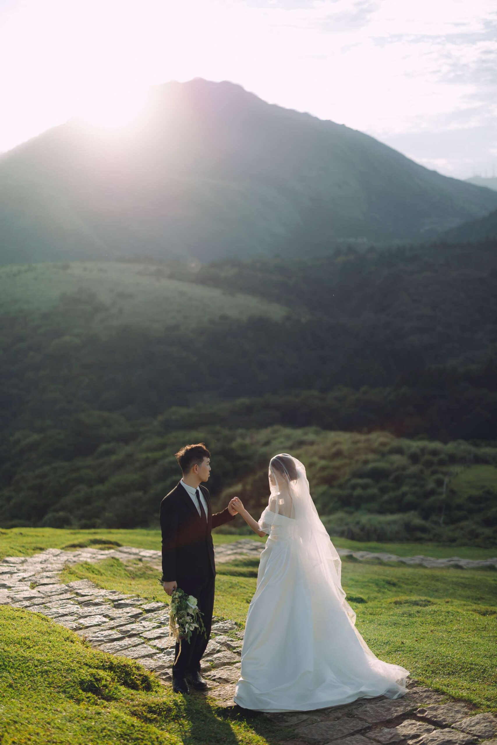 陽明山婚紗夕陽逆光,新人手牽手漫步在夕陽餘暉的石岩步道上,走向金色大山背影的感性牽手照。